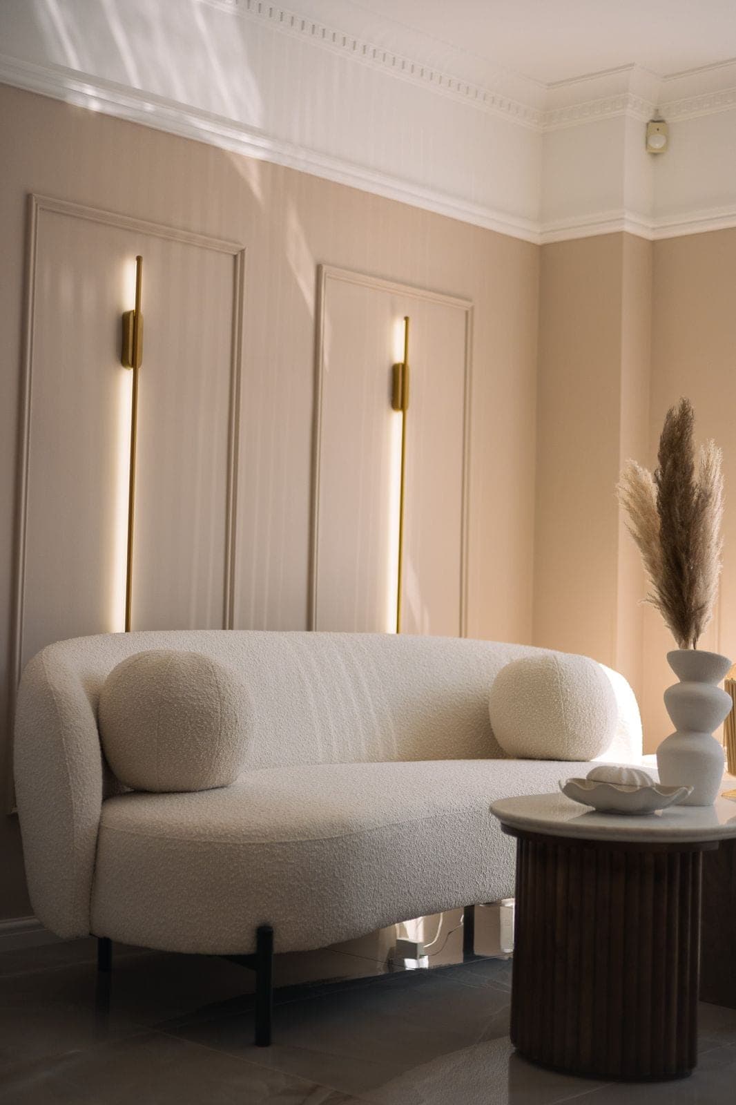 The clinic's lounge seating area, empty, with gold wall lighting and warm cream tones.